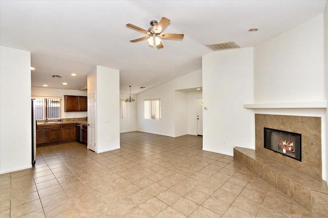 unfurnished living room featuring a tile fireplace, ceiling fan, light tile patterned floors, and vaulted ceiling