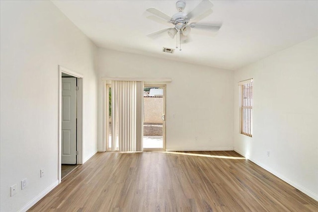 spare room with plenty of natural light, vaulted ceiling, and hardwood / wood-style flooring