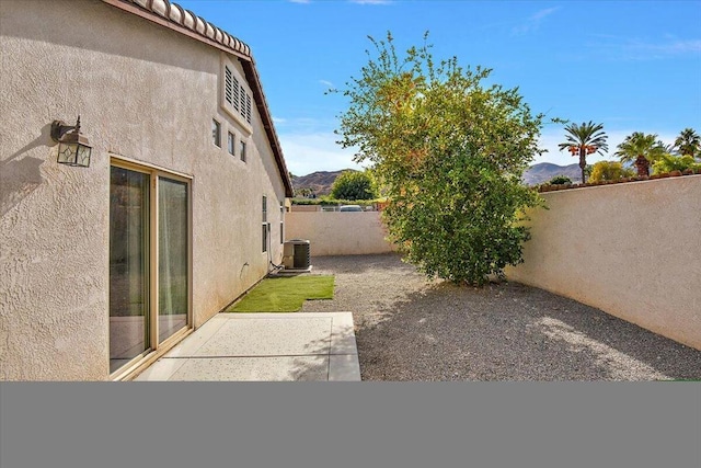 view of yard featuring a mountain view, central air condition unit, and a patio