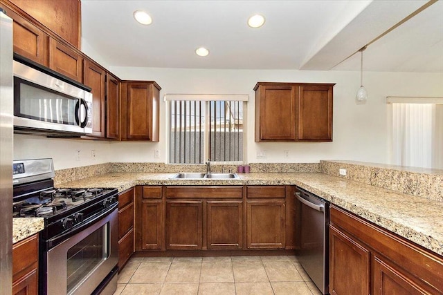 kitchen with appliances with stainless steel finishes, light tile patterned floors, pendant lighting, and sink