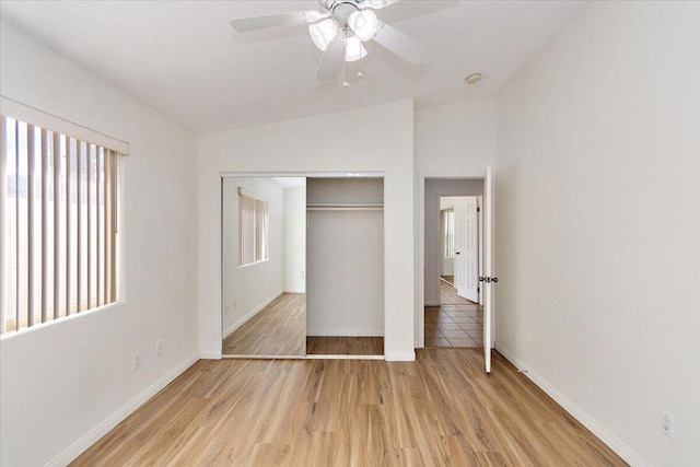 unfurnished bedroom featuring a closet, multiple windows, lofted ceiling, and light hardwood / wood-style floors