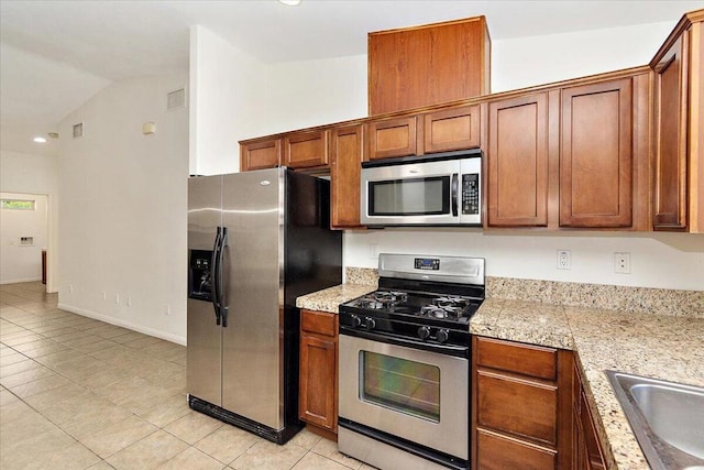 kitchen with light tile patterned flooring, sink, stainless steel appliances, and vaulted ceiling