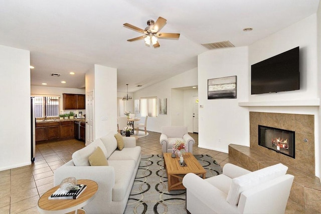 living room featuring ceiling fan, light tile patterned floors, a fireplace, and vaulted ceiling