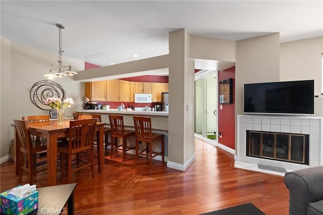 dining room featuring a tile fireplace, an inviting chandelier, and hardwood / wood-style flooring