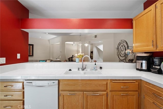 kitchen with sink, kitchen peninsula, tile countertops, white dishwasher, and decorative light fixtures