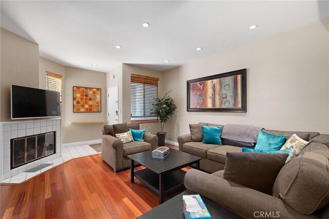 living room featuring light wood-type flooring and a tiled fireplace