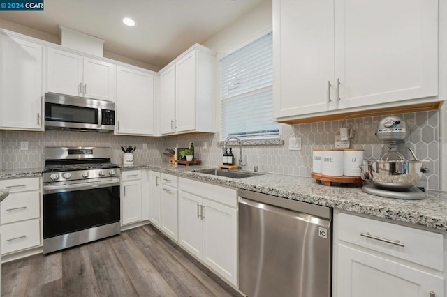 kitchen featuring appliances with stainless steel finishes, tasteful backsplash, sink, wood-type flooring, and white cabinets