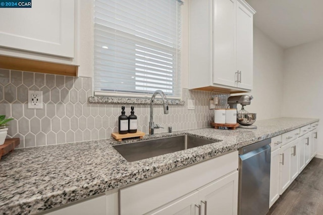 kitchen with light stone counters, stainless steel dishwasher, dark wood-type flooring, sink, and white cabinets