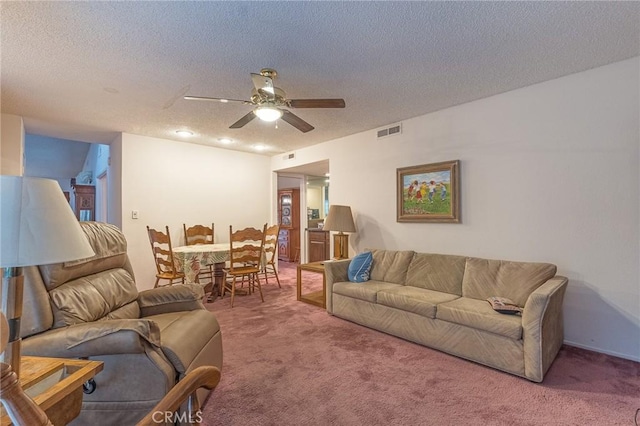 carpeted living room featuring ceiling fan and a textured ceiling