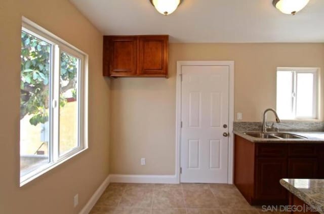 kitchen with light stone countertops, sink, light tile patterned floors, and a healthy amount of sunlight