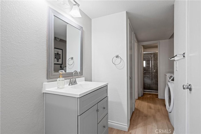 bathroom featuring vanity, independent washer and dryer, a textured ceiling, an enclosed shower, and wood-type flooring