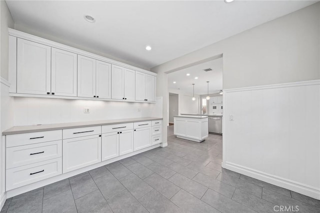 kitchen featuring white cabinets, stainless steel dishwasher, and hanging light fixtures