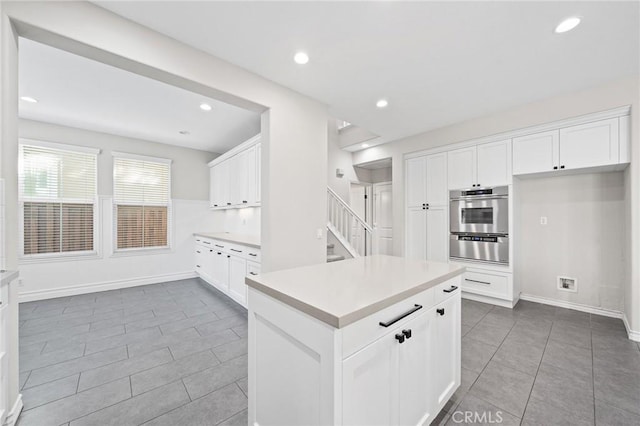 kitchen featuring tile patterned flooring, a center island, white cabinetry, and oven