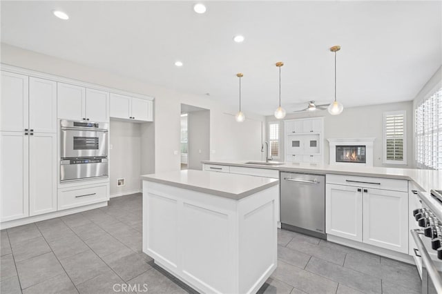 kitchen featuring sink, white cabinets, pendant lighting, a kitchen island, and appliances with stainless steel finishes