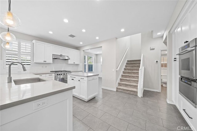 kitchen with pendant lighting, sink, light tile patterned floors, white cabinetry, and stainless steel appliances