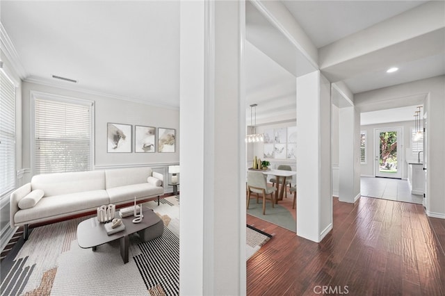 living room featuring crown molding, dark hardwood / wood-style floors, and an inviting chandelier