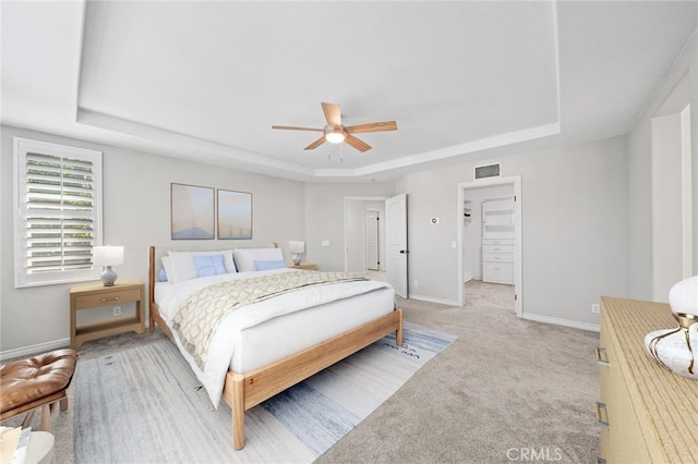 carpeted bedroom with ceiling fan and a raised ceiling