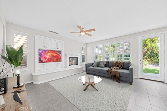 living room featuring light tile patterned floors, ceiling fan, and a healthy amount of sunlight