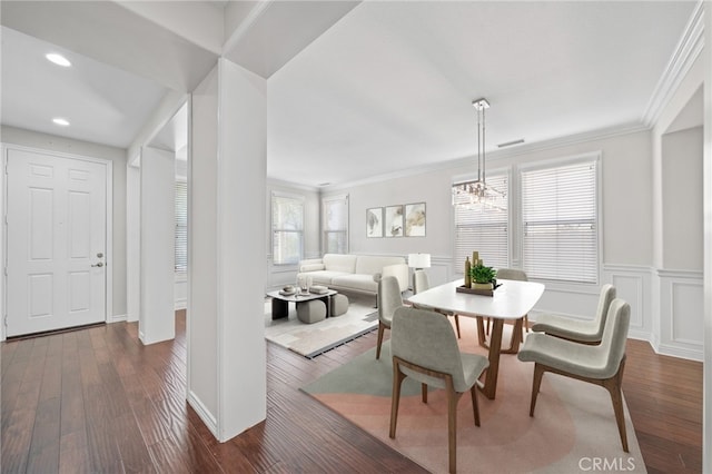 dining area featuring ornamental molding, dark wood-type flooring, and an inviting chandelier