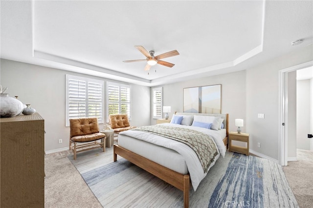 carpeted bedroom featuring ceiling fan and a raised ceiling