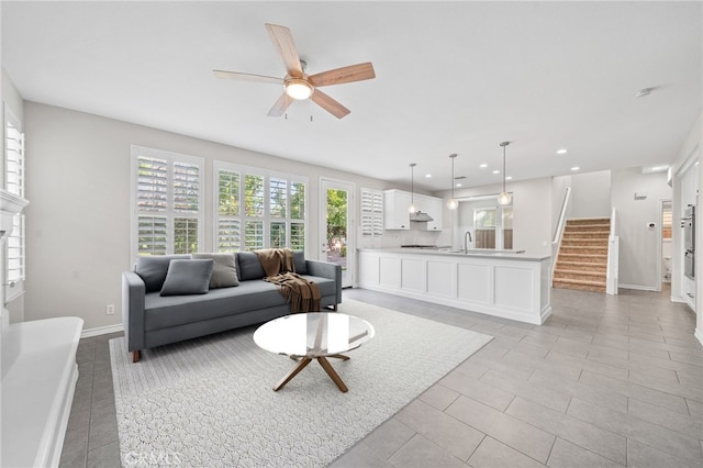 tiled living room with ceiling fan and sink