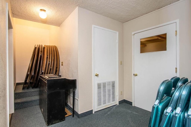 hall with dark colored carpet and a textured ceiling