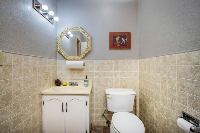 bathroom with vanity, tile walls, and toilet