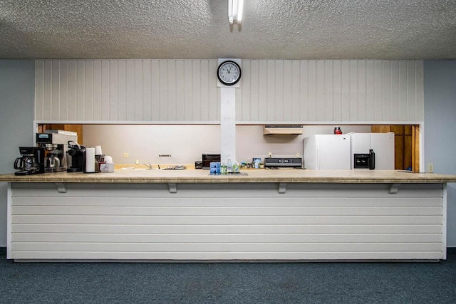 kitchen with dark carpet, white refrigerator with ice dispenser, kitchen peninsula, and exhaust hood