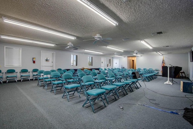 miscellaneous room with ceiling fan, carpet floors, and a textured ceiling