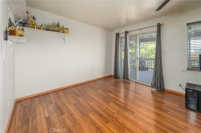 unfurnished room featuring wood-type flooring, a wealth of natural light, and ceiling fan