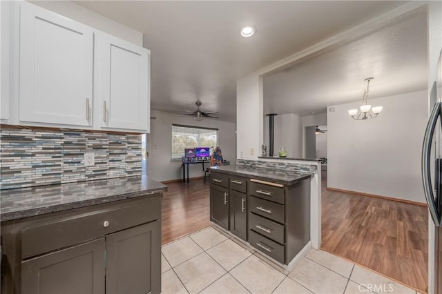 kitchen with white cabinets, decorative light fixtures, ceiling fan with notable chandelier, and light hardwood / wood-style floors