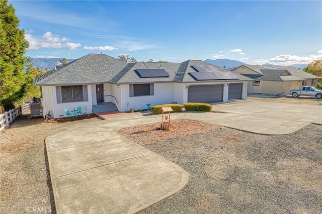 ranch-style home featuring a mountain view, solar panels, and a garage