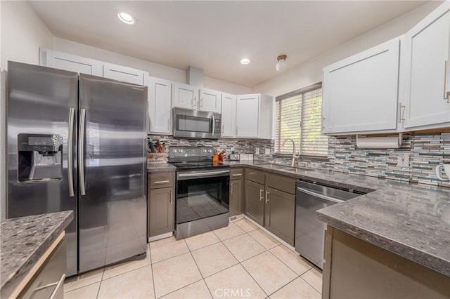 kitchen with appliances with stainless steel finishes, backsplash, white cabinetry, and dark stone countertops