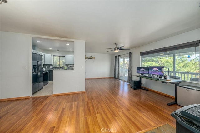 unfurnished living room featuring ceiling fan and light wood-type flooring