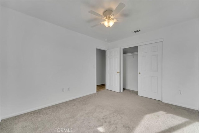 unfurnished bedroom with a closet, light colored carpet, and ceiling fan