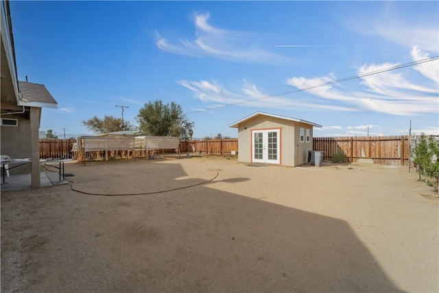 view of yard featuring a patio area, french doors, and an outdoor structure