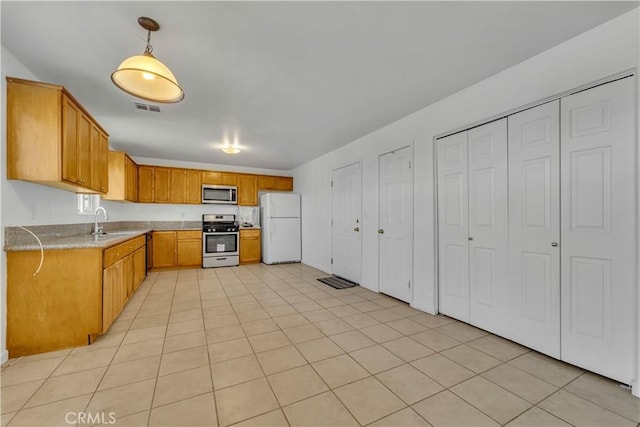 kitchen with pendant lighting, light tile patterned floors, sink, and appliances with stainless steel finishes