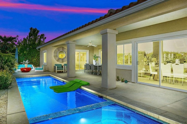 pool at dusk with a patio area and ceiling fan