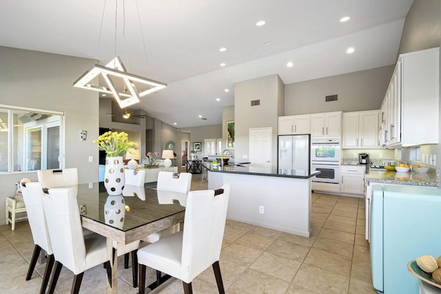 dining area with light tile patterned flooring, a healthy amount of sunlight, and high vaulted ceiling