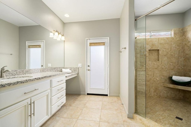 bathroom featuring tile patterned flooring, vanity, and a tile shower