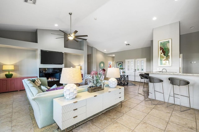 living room featuring ceiling fan, a high end fireplace, light tile patterned floors, and high vaulted ceiling