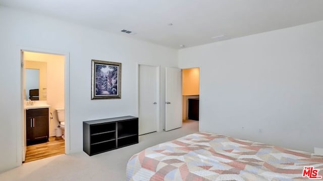 bedroom with light colored carpet and ensuite bath