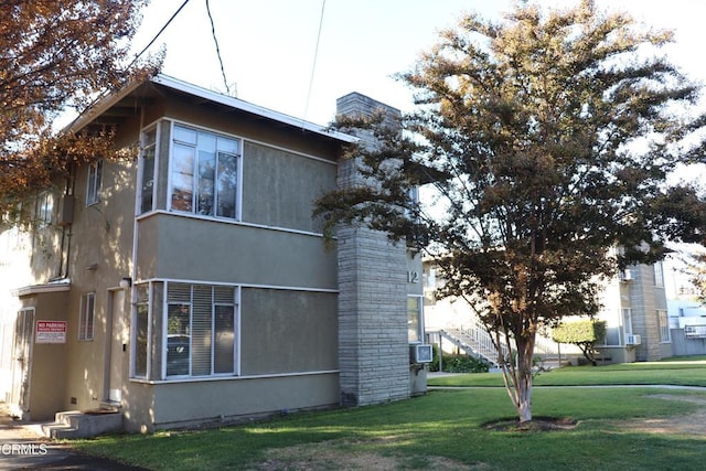 view of side of home featuring cooling unit and a lawn