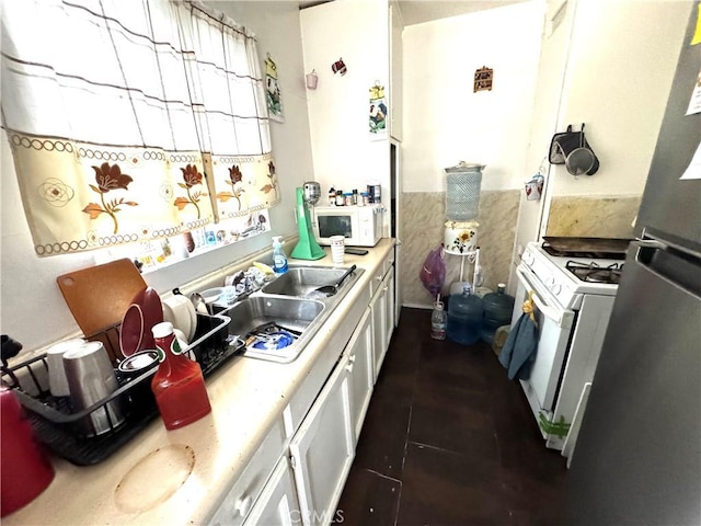 kitchen with white cabinetry, sink, dark tile patterned flooring, and white appliances