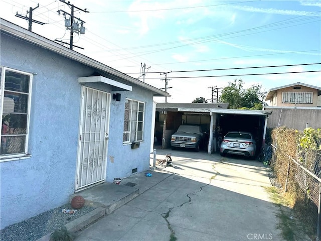 garage featuring a carport, concrete driveway, and fence