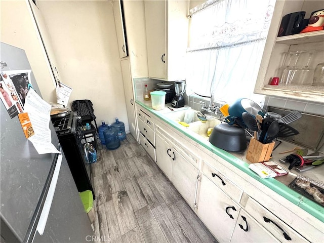 kitchen featuring white cabinets, light hardwood / wood-style floors, tile countertops, and sink