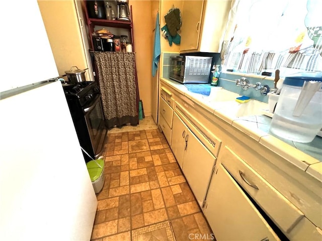 kitchen with tile countertops, white cabinetry, stainless steel appliances, and sink