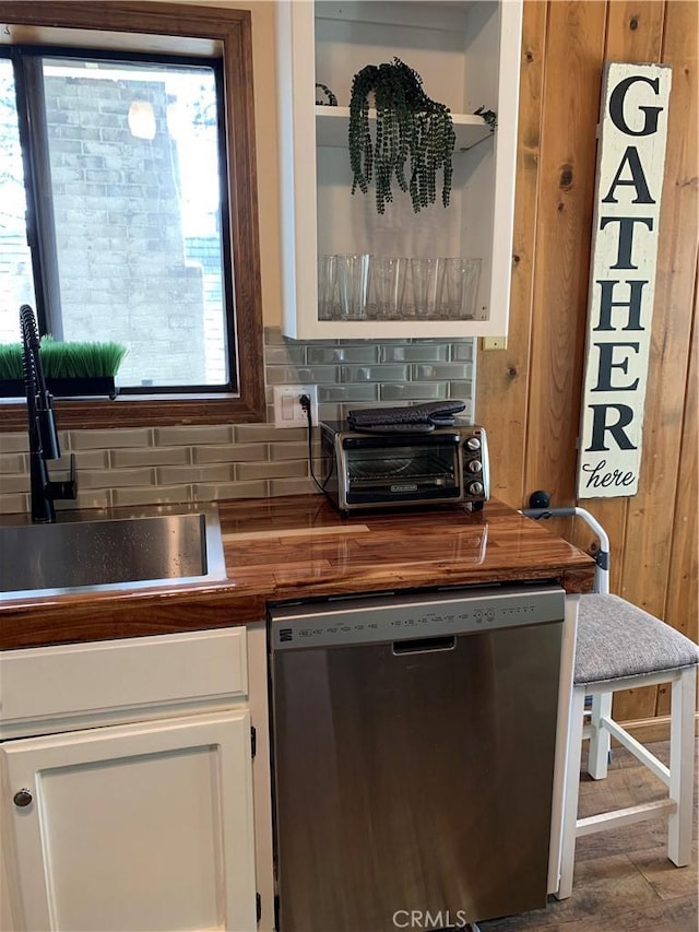 interior space with a wealth of natural light, white cabinetry, stainless steel dishwasher, and sink