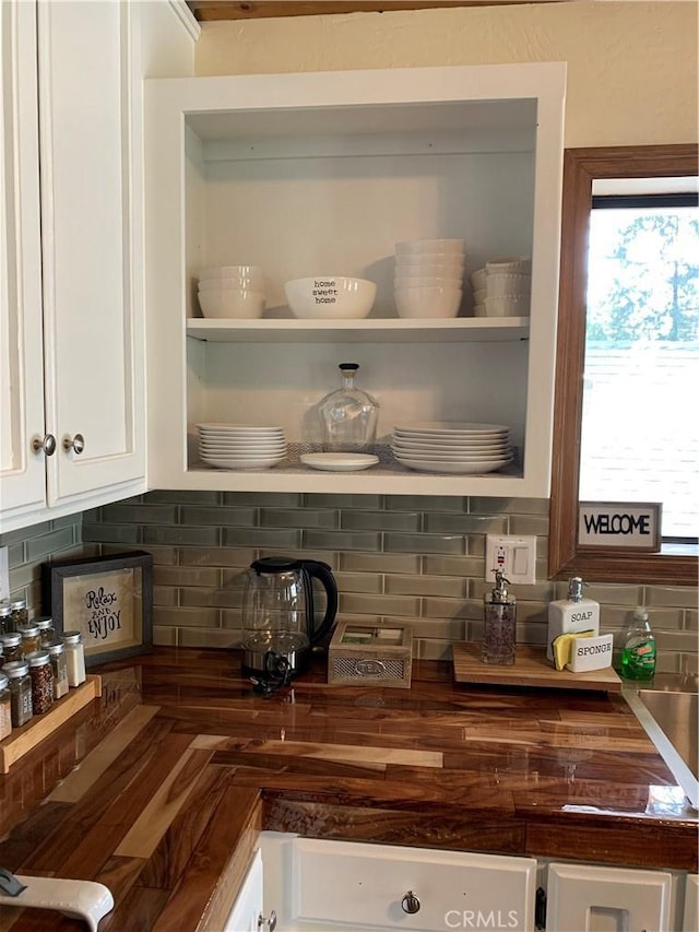 details featuring tasteful backsplash, butcher block counters, and white cabinetry