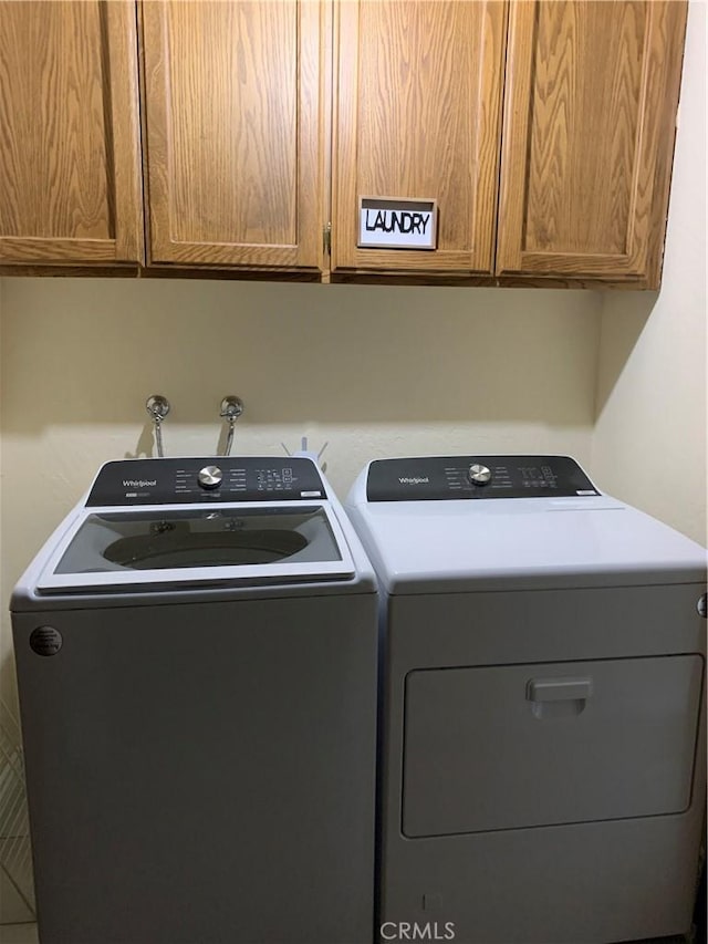 clothes washing area featuring cabinets, separate washer and dryer, and tile patterned floors